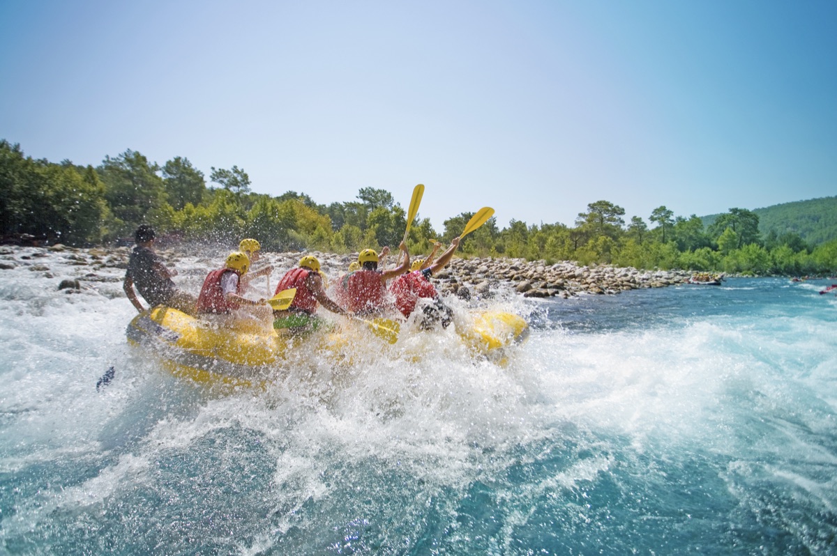 A team paddling a raft together through whitewater rapids